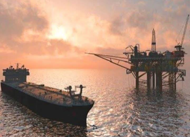 Buque tanque junto a una plataforma petrolera al atardecer